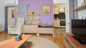 Un salon moderne avec un canapé, une table basse et un meuble pour la télévision. Il y a également un coin cuisine avec des placards et une cuisinière.