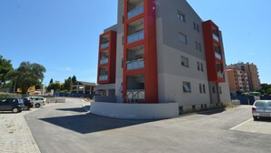 Un immeuble moderne à plusieurs étages, doté de balcons, d’une entrée principale et d’un espace de stationnement.