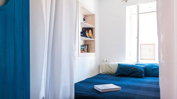Ein Schlafzimmer mit Bett, Bücherregal und Fenster.