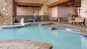 Ein Hallenbad mit Steinwänden, hölzernen Bänken und einer gefliesten Liegefläche.