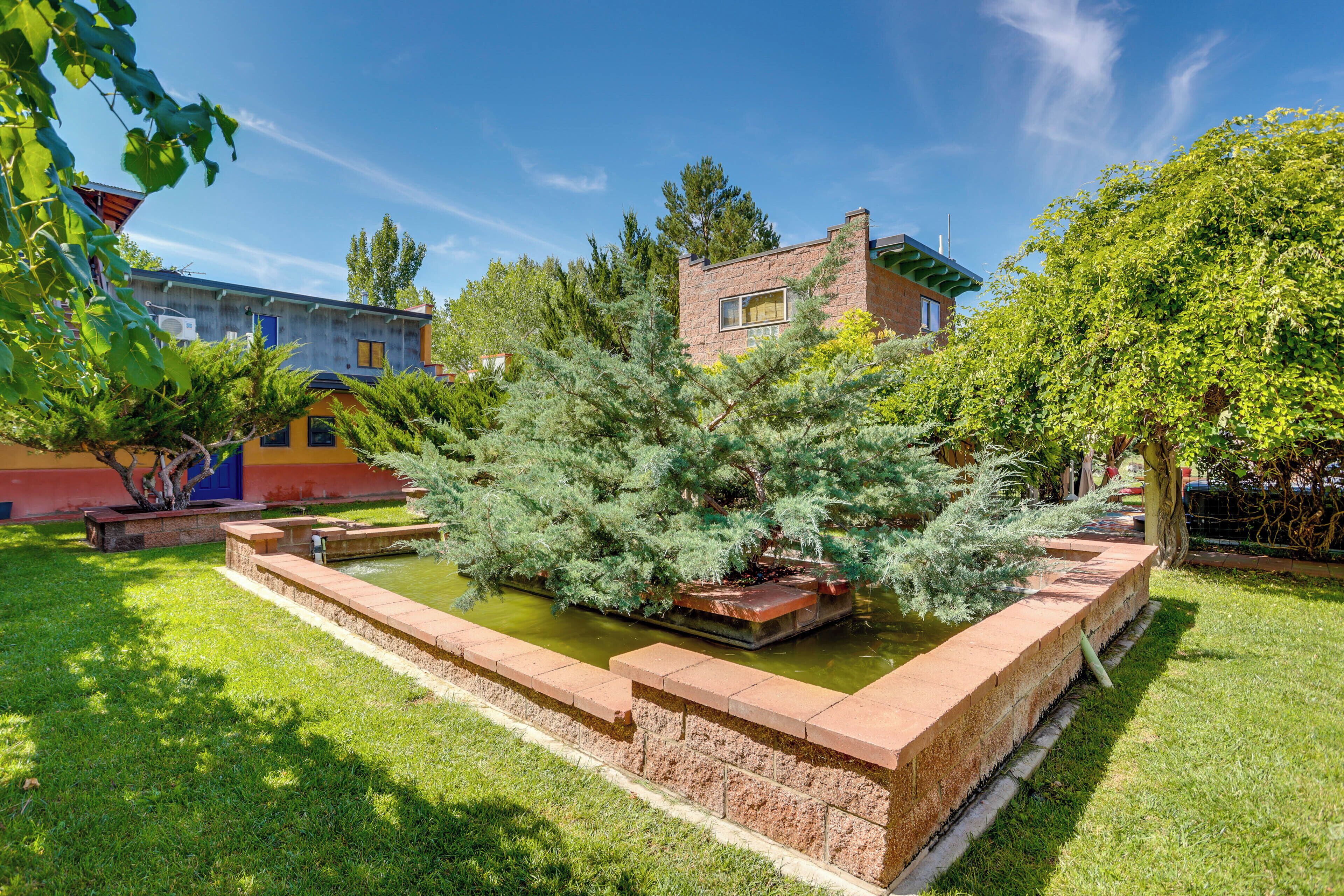 A courtyard with a water feature, a brick building, and surrounding greenery.