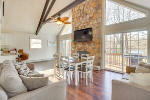 Relax in this spacious living area with a high ceiling, featuring a flat-screen TV, dining table, and comfortable seating.