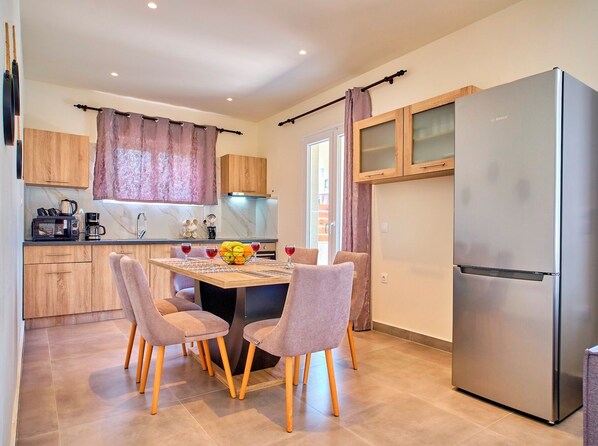 A modern kitchen with wooden cabinets, a stainless steel refrigerator, and a dining table with four chairs.