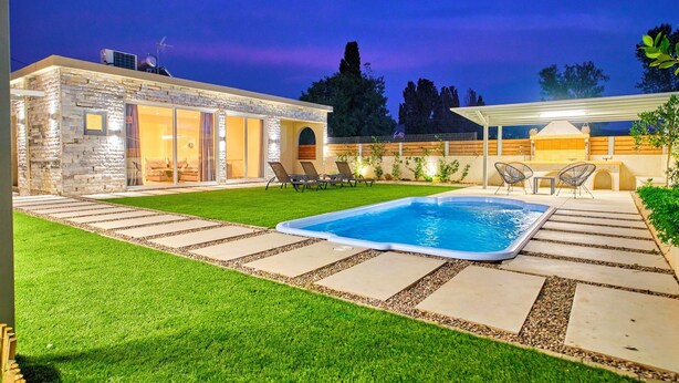 A backyard with a swimming pool, a stone building, and a covered patio area. - Villa Cinque Elementi by Estia (Ionian Islands)