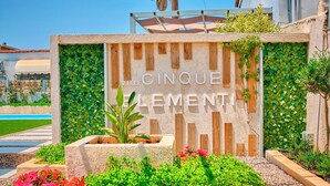 A sign with 'VILLE CINQUE ELEMENTI' and a garden area with plants and flowers. - Villa Cinque Elementi by Estia (Ionian Islands)