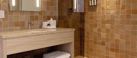 Une salle de bain moderne avec un meuble-lavabo en bois, une cabine de douche en verre et un mur recouvert de carreaux.