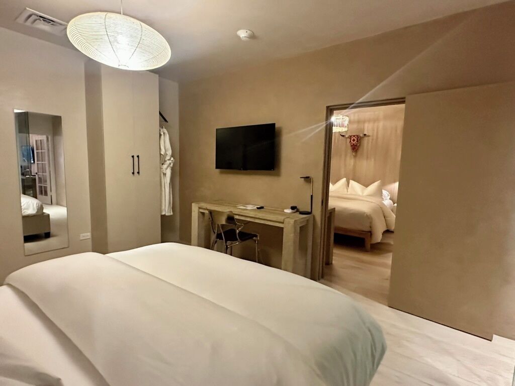 Une chambre d’hôtel avec un grand lit, un bureau avec une chaise, une télévision et un miroir.