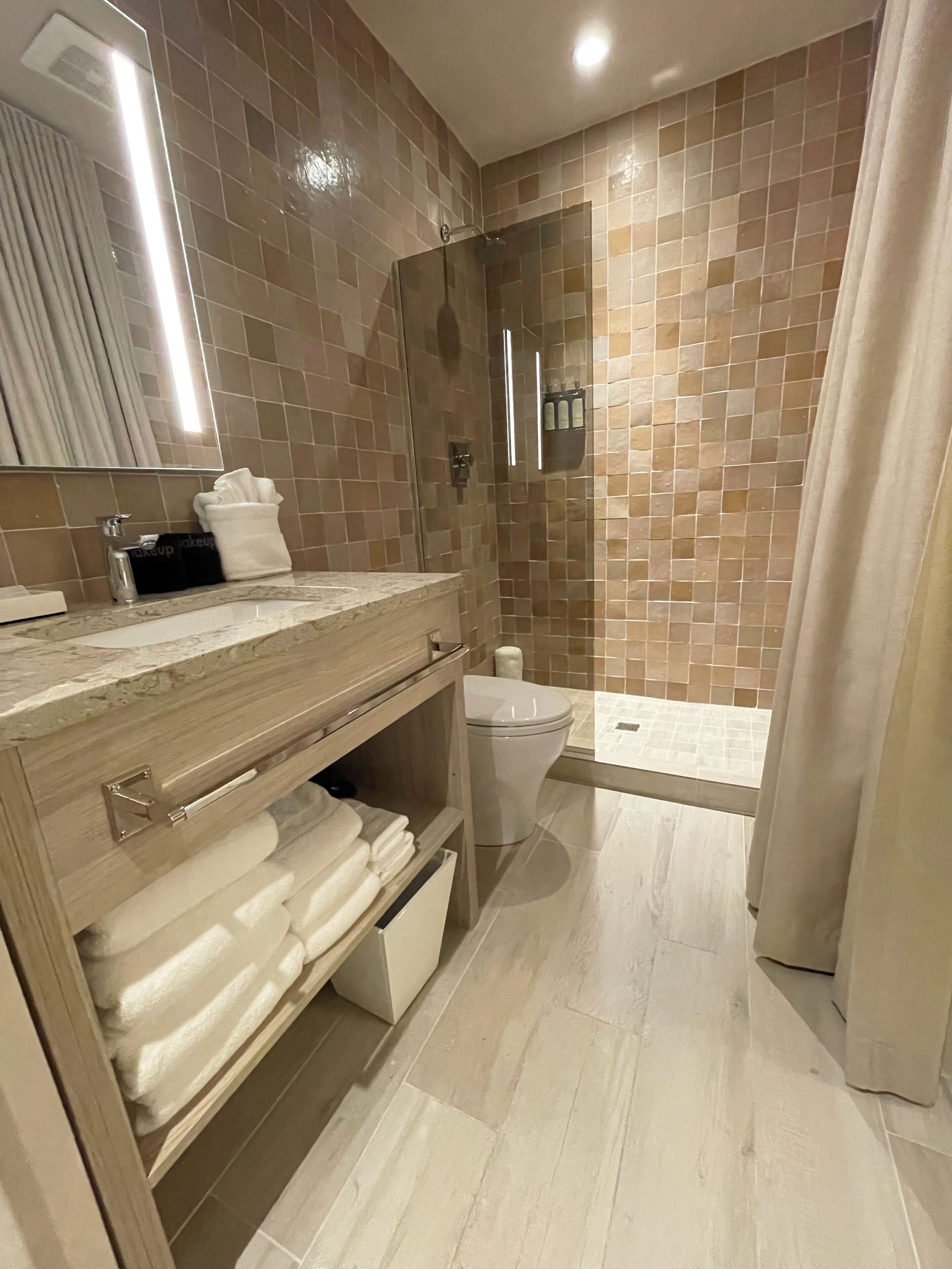 Ein modernes Badezimmer mit einer gläsernen Duschkabine, einem Waschtisch mit Stauraum und einer Toilette.