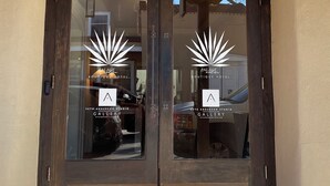 A wooden double door with glass panels, a number '105' above, and logos for 'Palace Boutique Hotel' and 'Seth Anderson Studio Gallery' on the glass. - Palace Modern Hotel at the Plaza (Santa Fe)