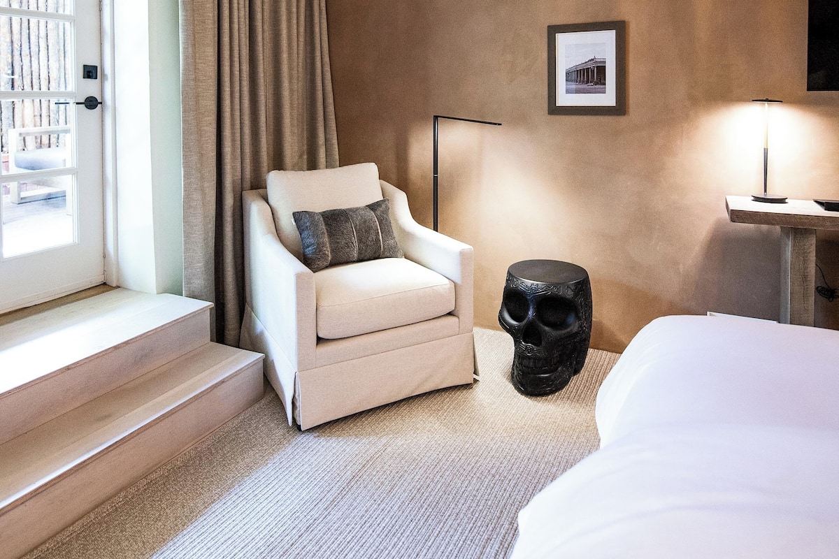 Une chambre d’hôtel avec un grand lit, une chaise, une lampe sur pied et une vue sur l’extérieur.
