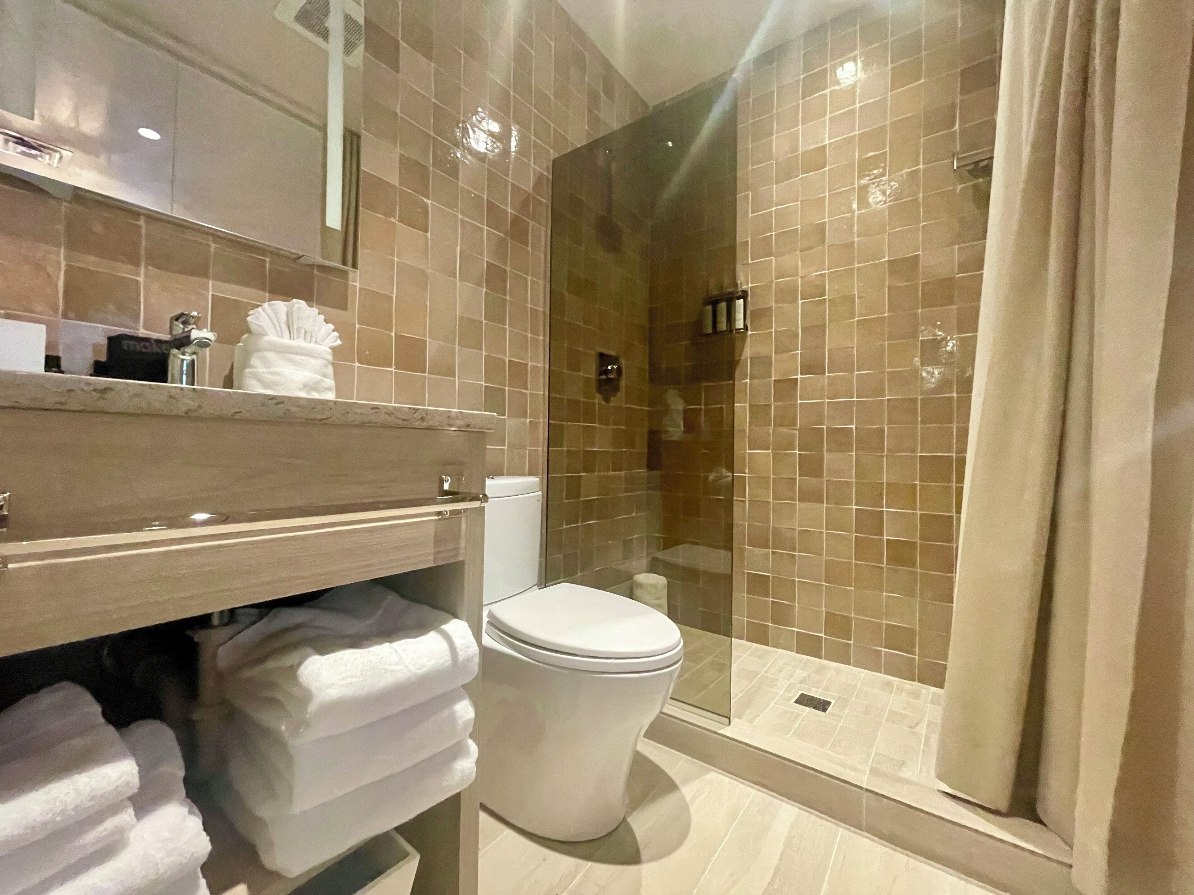 Ein modernes Badezimmer mit einer Duschkabine, einer Toilette und einem Waschtisch mit Handtüchern.