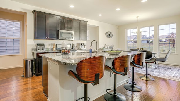 A kitchen with dark cabinets, a granite countertop, and a central island with bar stools. - Centrally Located Home in Fredericksburg! (Fredericksburg)