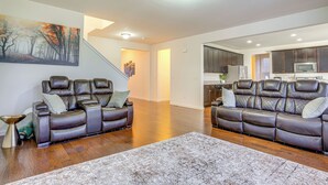 A spacious living room with two leather sofas, a large painting, and hardwood flooring. - Centrally Located Home in Fredericksburg! (Fredericksburg)