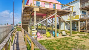 A beachfront house with a wooden deck and colorful Adirondack chairs. - Beachfront Cottage w/ Boardwalk in Freeport (Freeport)