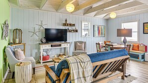 A cozy living room with a television, seating, and decorative items. - Beachfront Cottage w/ Boardwalk in Freeport (Freeport)