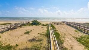 A beach with a wooden boardwalk leading to the ocean, sandy dunes, and a clear sky. - Beachfront Cottage w/ Boardwalk in Freeport (Freeport)