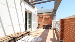 Eine Terrasse mit einer hölzernen Bank, einem Grill und einer Ziegelwand.