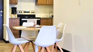 Una cocina moderna con armarios de madera, una estufa blanca y una mesa de comedor con cuatro sillas blancas.