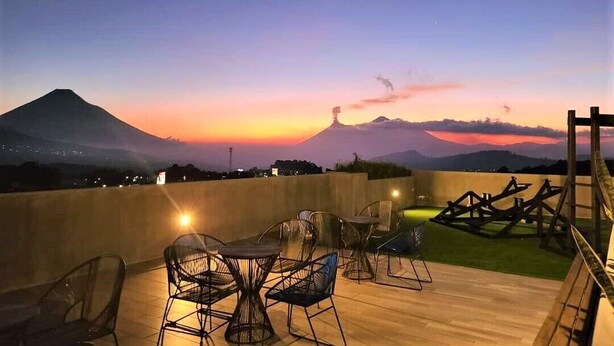 Una terraza con mobiliario exterior y vistas a una montaña al atardecer.