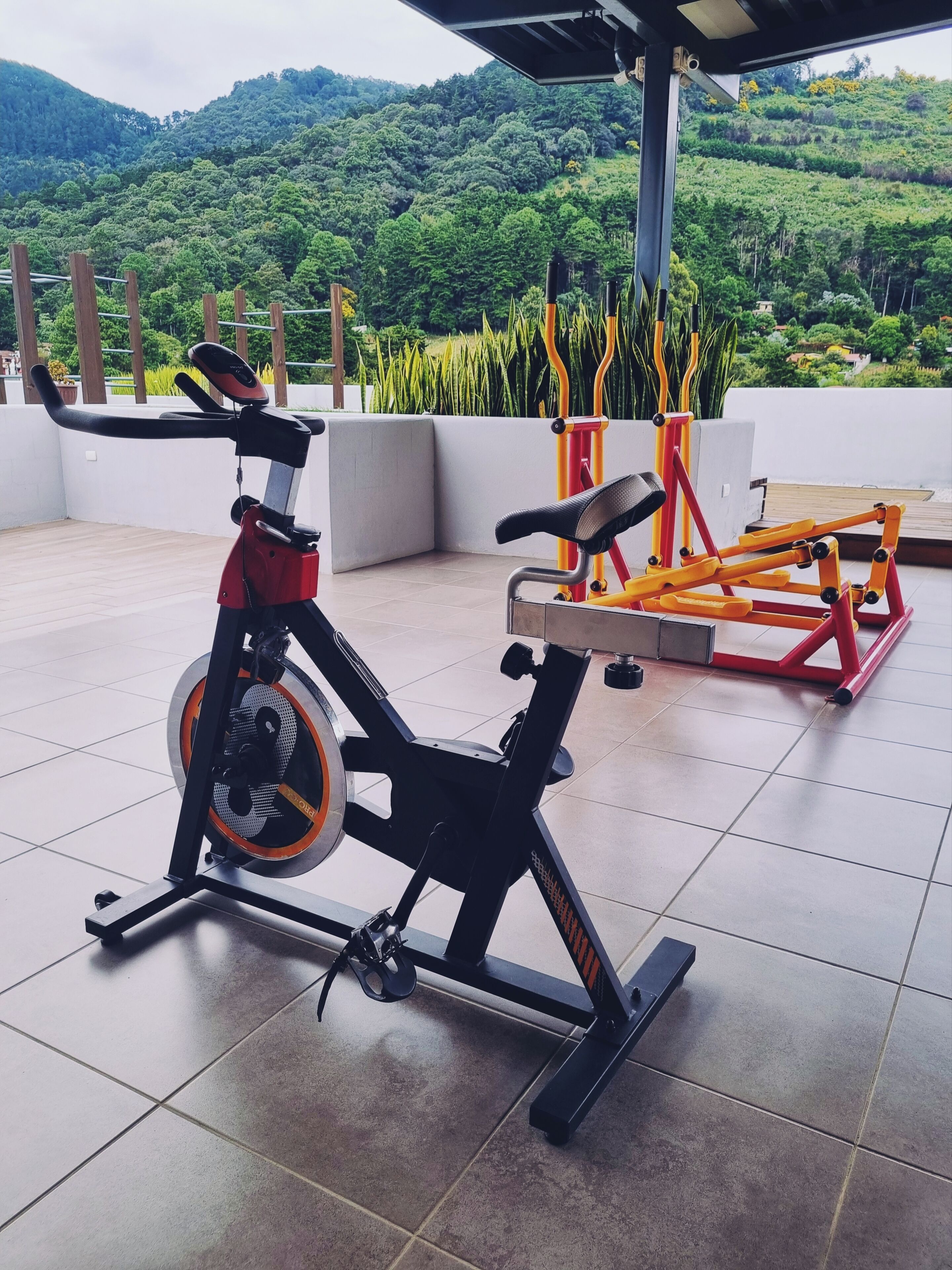 Ein Trainingsbereich im Freien mit Ergometer und Blick auf eine üppige, grüne Landschaft.
