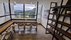 Una habitación moderna con un ventanal que ofrece vistas a la montaña, un banco de madera y una mesa con sillas.