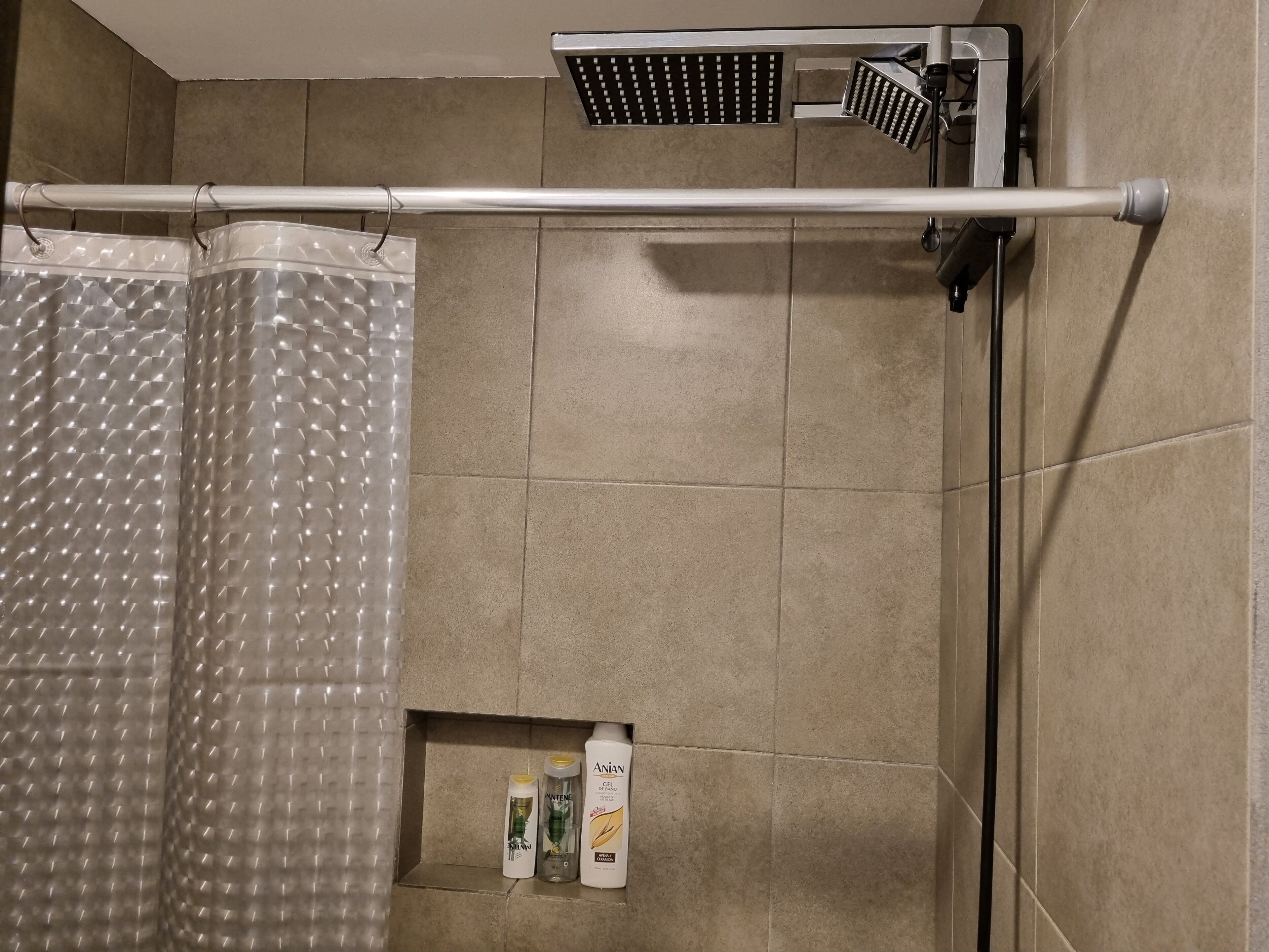 A shower area with a rain showerhead, a handheld showerhead, and a towel rack.