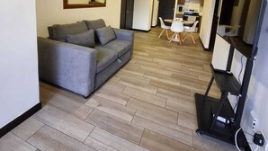 Una sala de estar moderna con un sofá gris, una mesita blanca y un mueble para televisión.