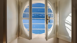An open window with a view of a body of water and buildings across it. - La Casa - Spacious apartment in historic villa with private lake access (Carate Urio)