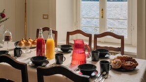 A dining table with breakfast items, a lamp, and a view of a lake and mountains. - La Casa - Spacious apartment in historic villa with private lake access (Carate Urio)