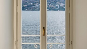 A room with a view of a lake and mountains through a window. - La Casa - Spacious apartment in historic villa with private lake access (Carate Urio)