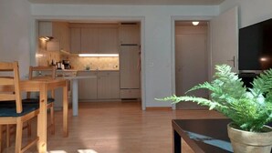 A modern kitchen with wooden cabinets, a dining table with chairs, and a potted plant. - Charming 2-bedroom apartment with WiFi in St. Gallen (St. Gallen)