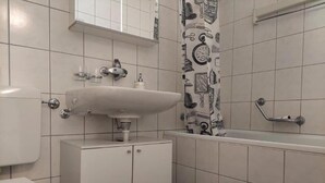 A bathroom with a white sink, toilet, and bathtub. - Charming 2-bedroom apartment with WiFi in St. Gallen (St. Gallen)
