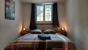 A bedroom with a large bed, two bedside lamps, a window with curtains, and a painting on the wall. - Charming 2-bedroom apartment with WiFi in St. Gallen (St. Gallen)