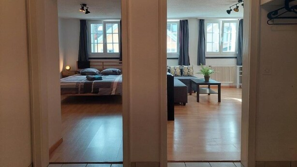A room with a bed, bedside table, and a window. - Charming 2-bedroom apartment with WiFi in St. Gallen (St. Gallen)