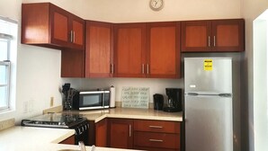 A kitchen with wooden cabinets, a stainless steel refrigerator, a microwave, a stove, and a sink.