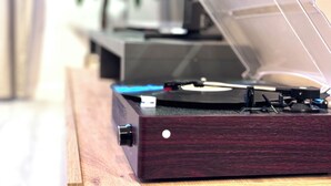 A turntable on a wooden surface with a plant in the background.