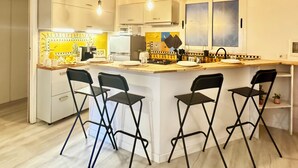 A modern kitchen with a central island, bar stools, and a dining area.