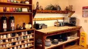 A kitchen with wooden shelves holding mugs and tea boxes, a coffee machine, and a toaster. - UU Rowe Camp and Conference Center (Rowe)