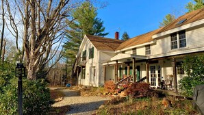 A two-story house with a porch and a staircase leading to the upper floor. - UU Rowe Camp and Conference Center (Rowe)