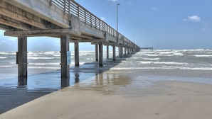 A concrete pier extending into the ocean with a clear sky above.