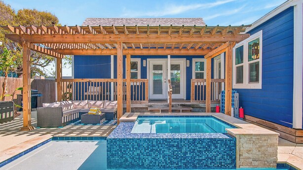 A backyard with a swimming pool, wooden pergola, and outdoor seating.