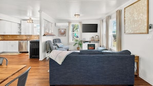 A modern interior with a dining area, kitchen, and living room with a fireplace.