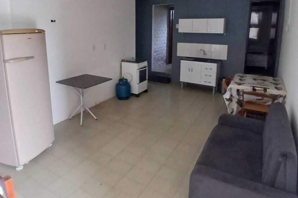 Ein gemütlicher Wohnraum mit Küchenzeile, einer Couch, einem kleinen Esstisch und einem Kühlschrank.