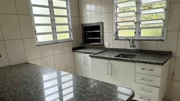 Una cocina con armarios blancos, una encimera de granito y un microondas integrado.