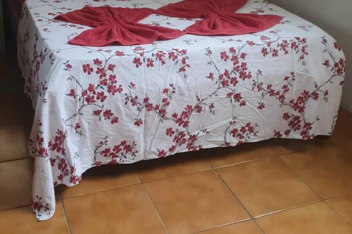 Ein Bett mit blumigem Überwurf, einer roten Decke und einem hölzernen Kopfteil.