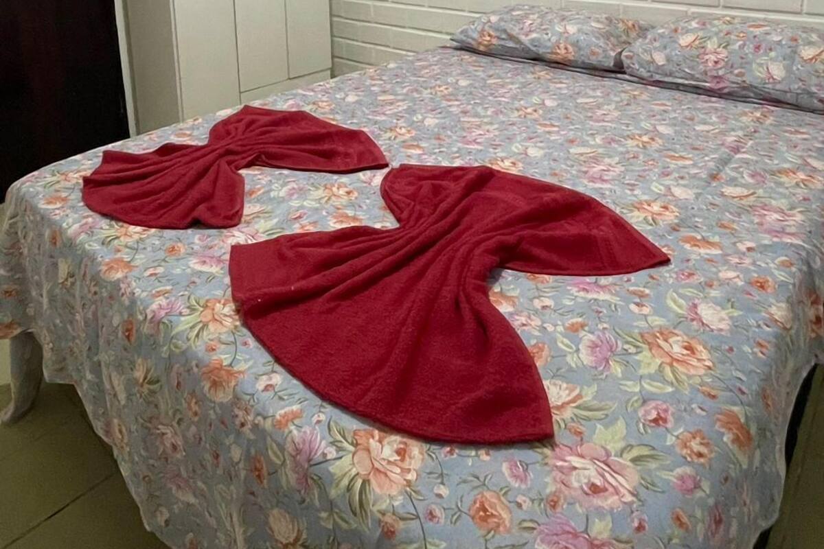 Ein Schlafzimmer mit einer blumigen Tagesdecke, einer Holzbalkendecke und einer weißen Ziegelwand.