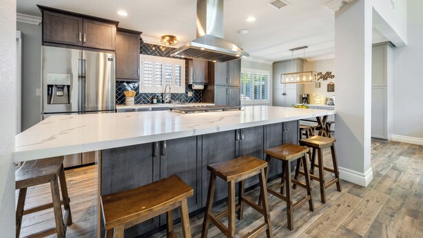 A modern kitchen with a large island, bar stools, and a built-in coffee station.