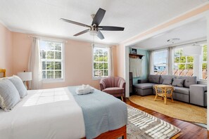 Un dormitorio con cama, ventilador de techo, sofá y sillón.