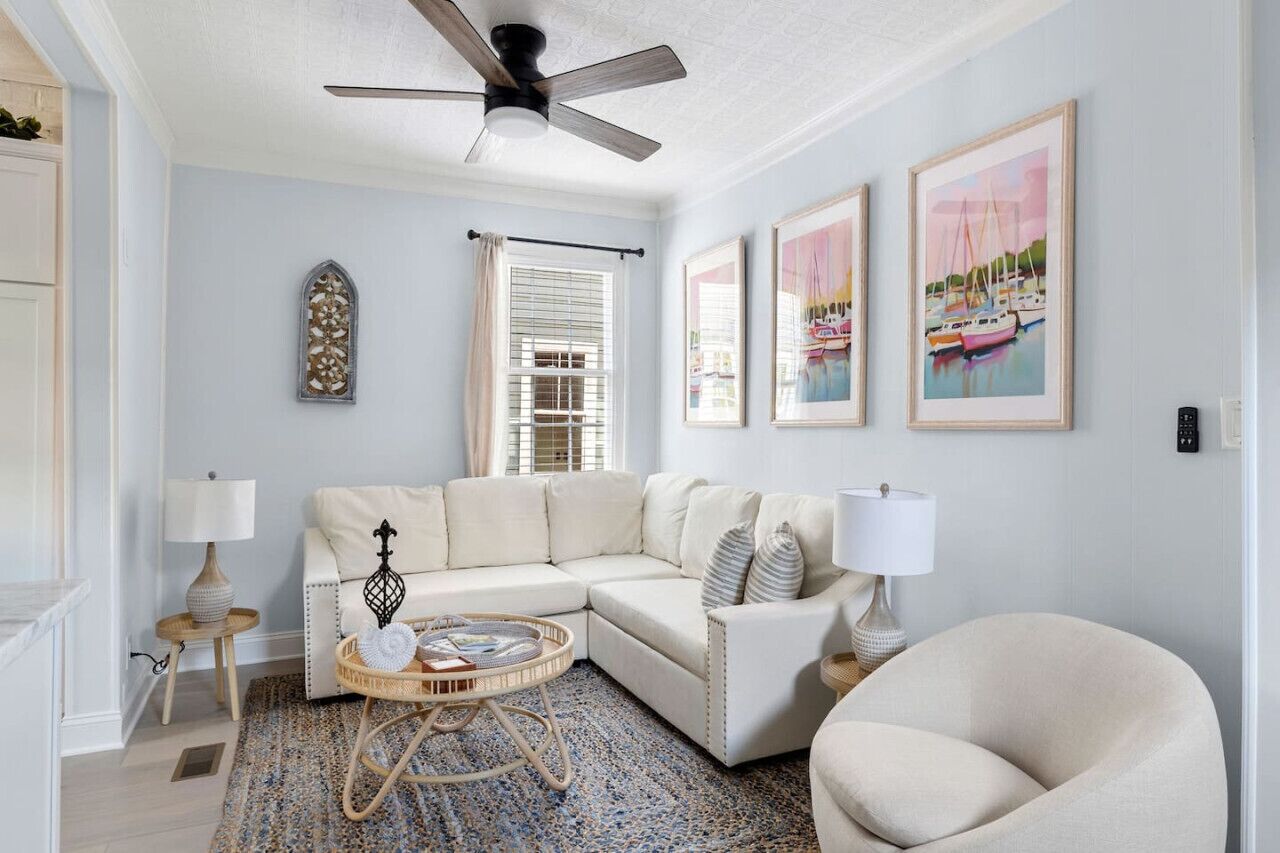A living room with a sectional sofa, a round coffee table, a floor lamp, and framed artwork on the wall.