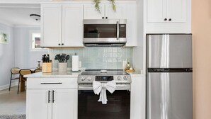 A modern kitchen with white cabinetry, a stainless steel refrigerator, a microwave, and an oven.